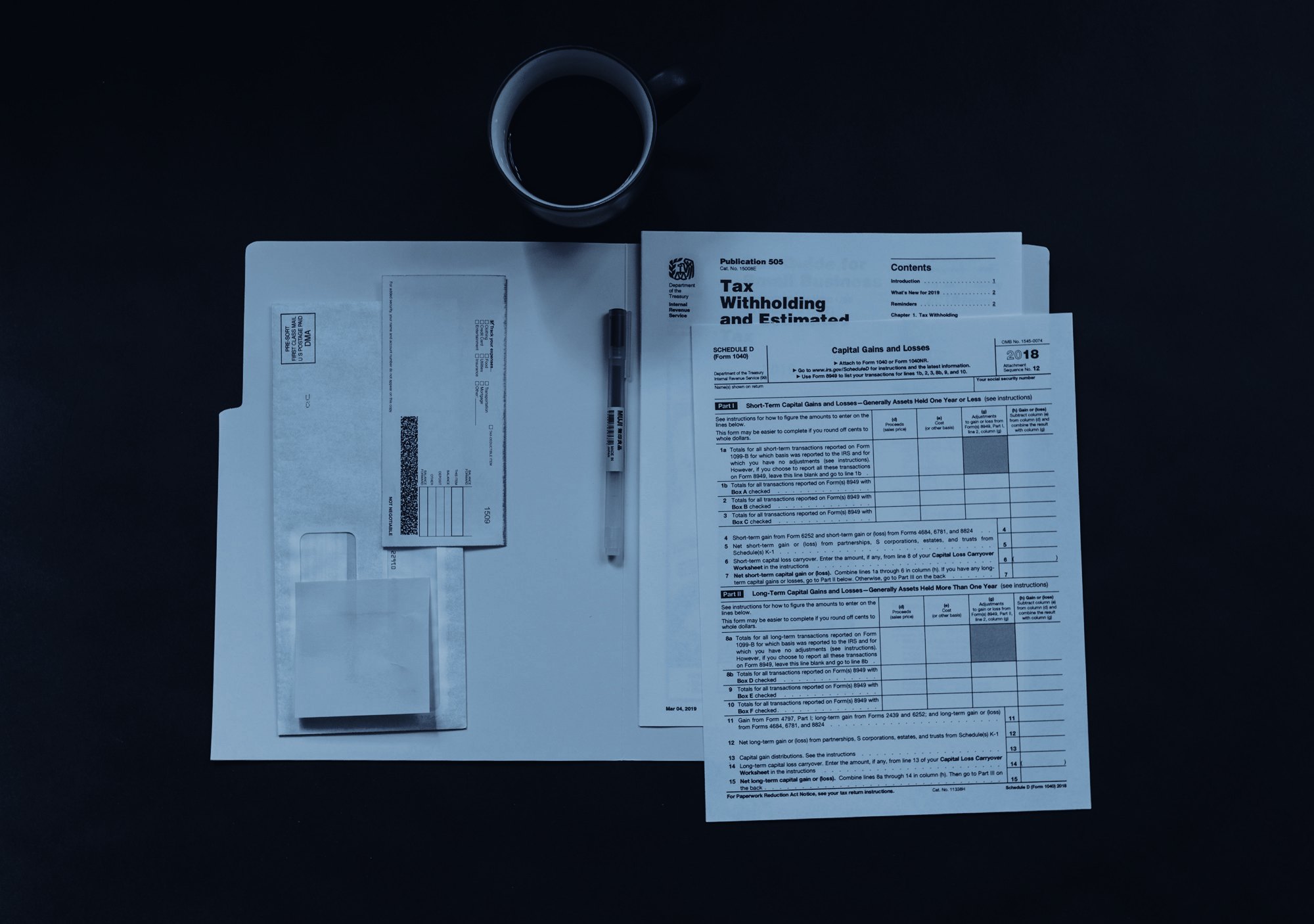 Forms, a pen and a coffee cup on a dark desk